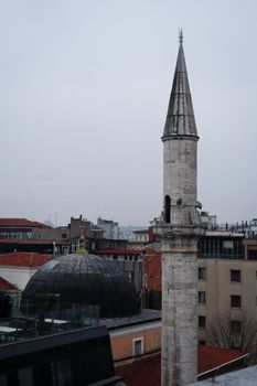A detailed view of an Ottoman minaret amid Istanbul's urban architecture.