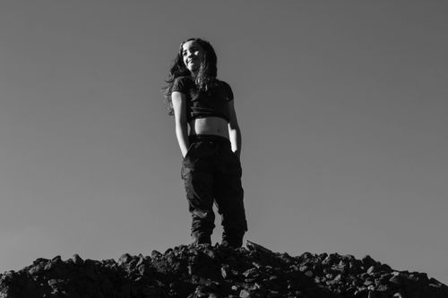 Free Artistic black and white photo of a woman standing on rocks under a clear sky. Stock Photo