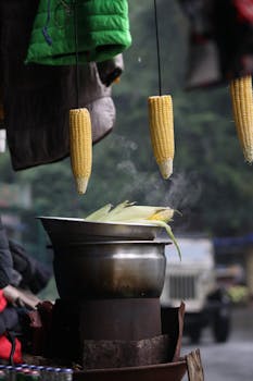 Steaming corn kernels being prepared at a street food stall, highlighting urban food culture vividly.