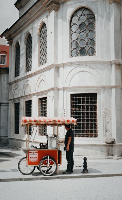 Street vendor with food cart in front of historic building. Urban lifestyle captured.
