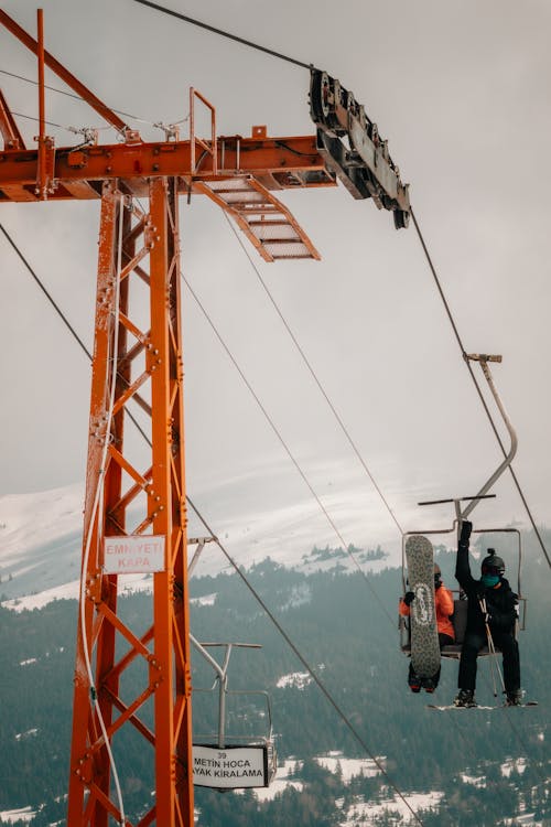 Two people on a ski lift with a mountain in the background