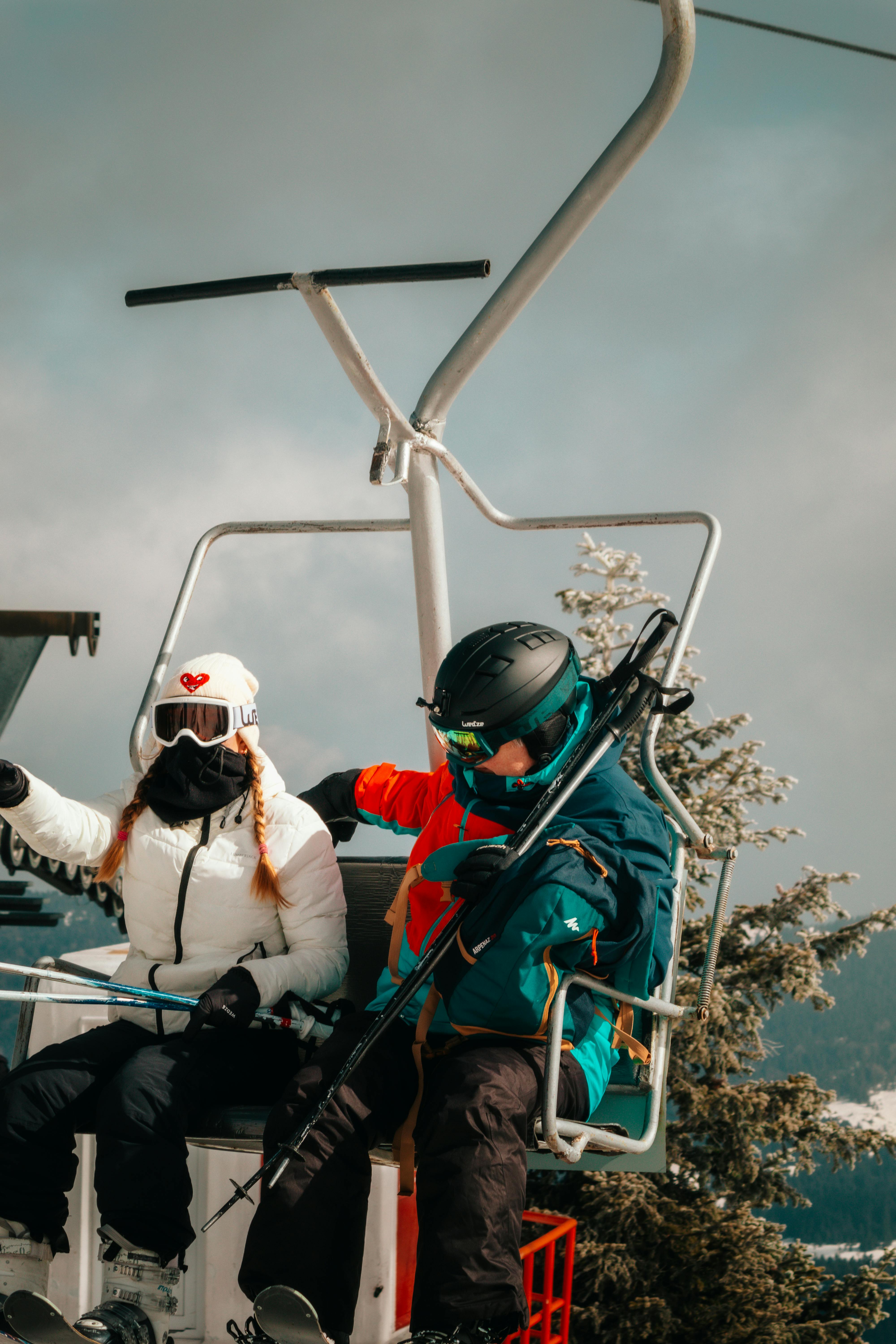 Prescription Goggle Inserts - Two skiers in winter gear enjoy a scenic ride on a ski lift, surrounded by snow.