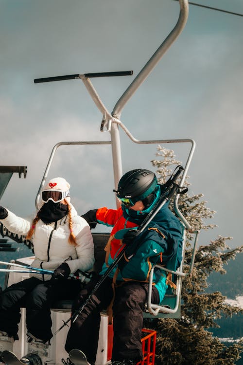Two people on a ski lift with skis on