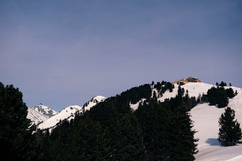 A snowy mountain with a small cabin on top