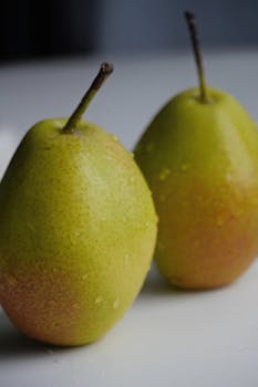 Two fresh pears with water droplets on a white background, perfect for food photography.