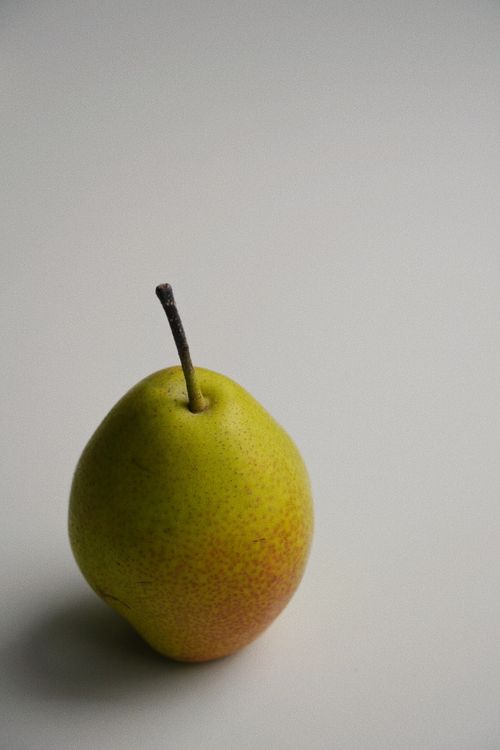 Free Artistic still life of a solitary pear on a simple background. Stock Photo