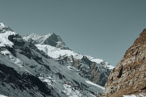 Free Majestic snowcapped mountain range with rugged rock formations, ideal for winter scenery lovers. Stock Photo