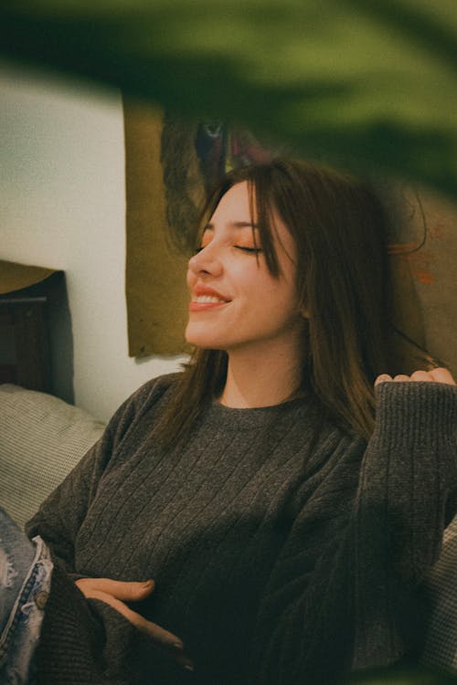 A woman is smiling while sitting on a couch