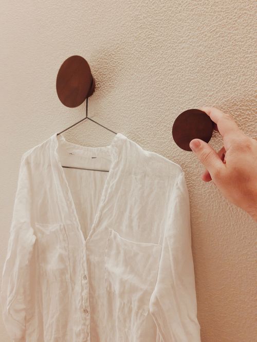 A plain white shirt on a wall hanger. Photo by tiago alves on Pexels.