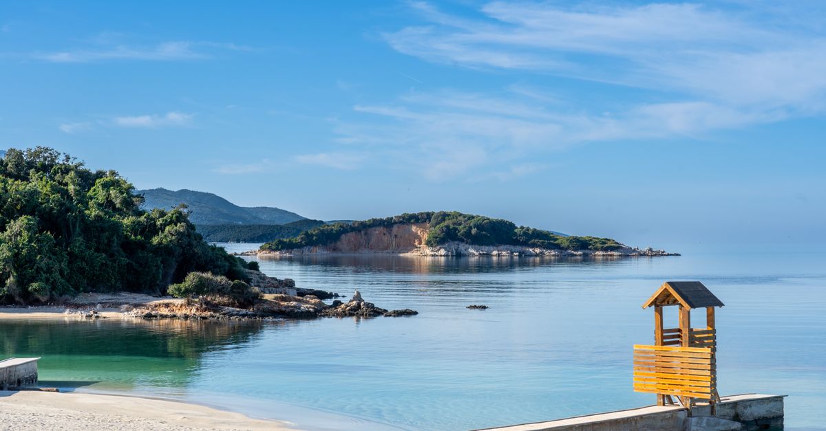 crystal clear turquoise water and white pebble beach on the Albanian Riviera in Ksamil, with mountains in background