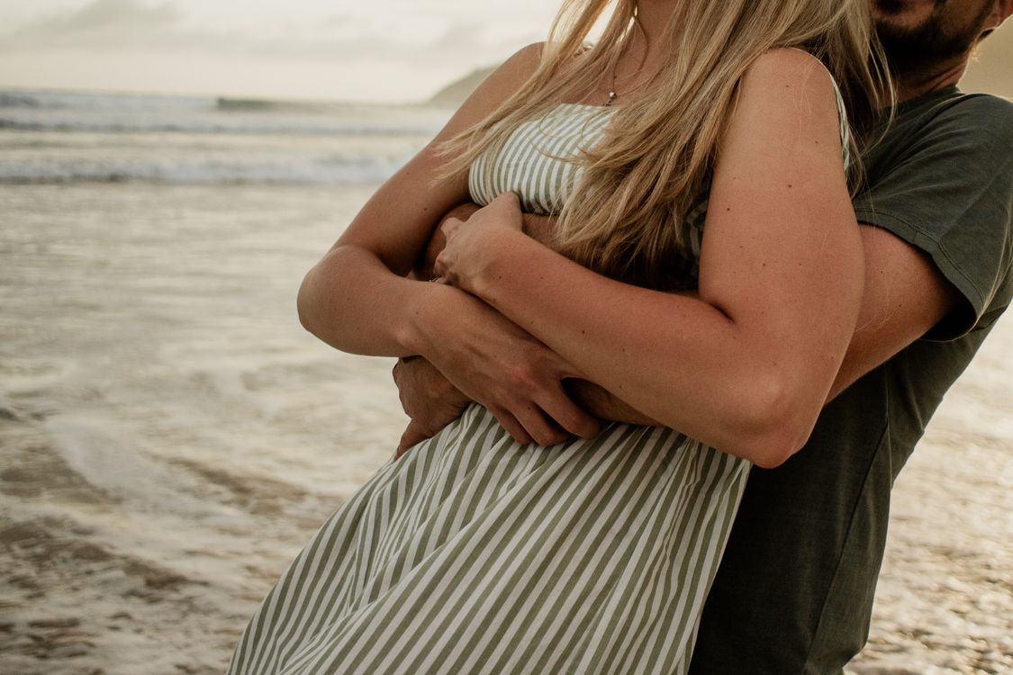 Man Hugging Woman in Sundress on Sea Shore · Free Stock Photo