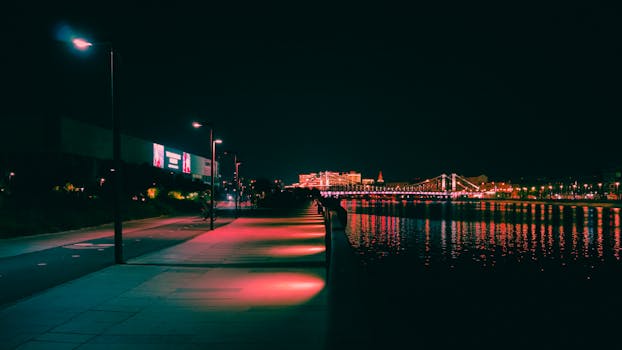 Captivating nighttime view of an illuminated walkway and bridge in Moscow by the river.