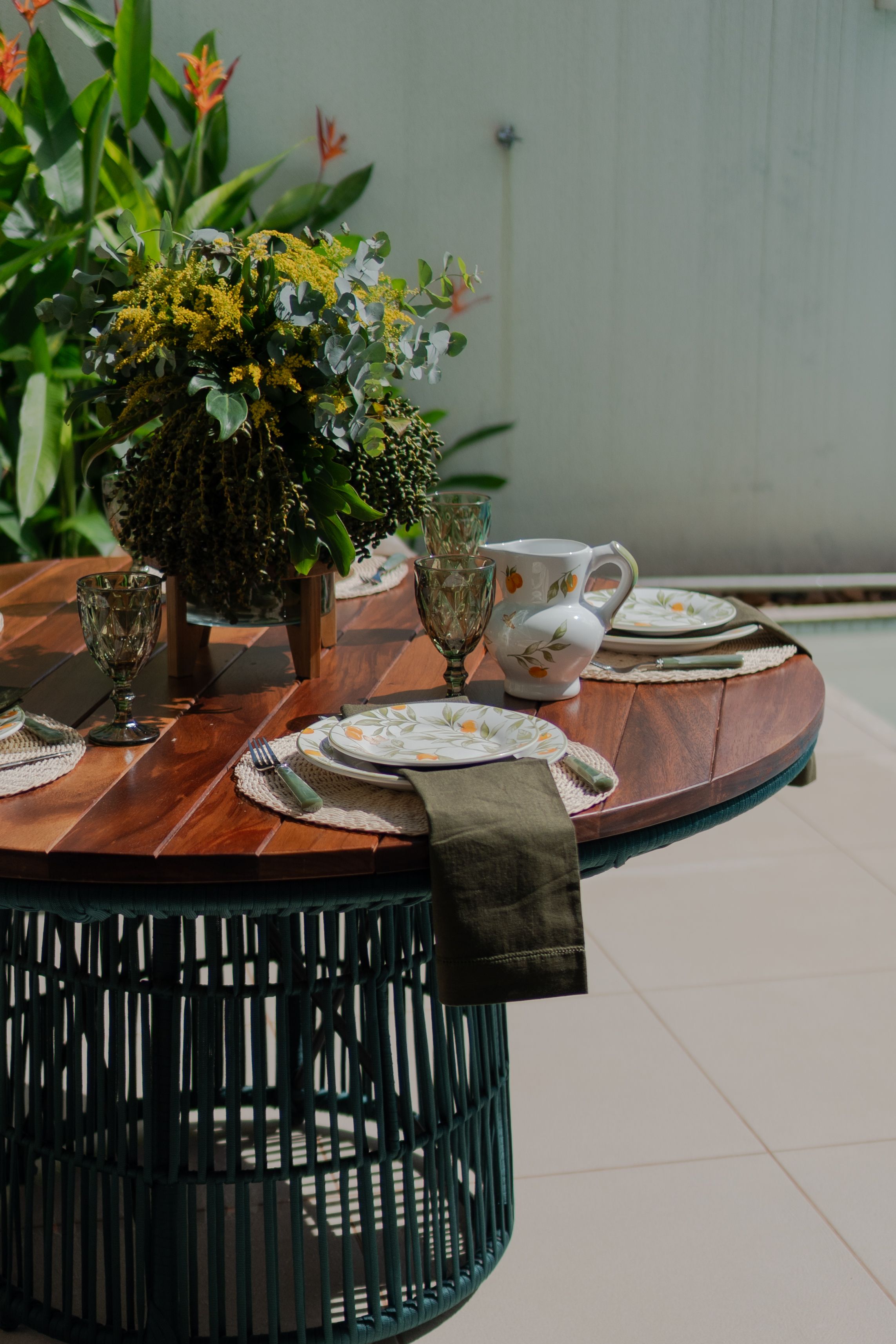A beautifully arranged summer outdoor table setting featuring flowers and plates.