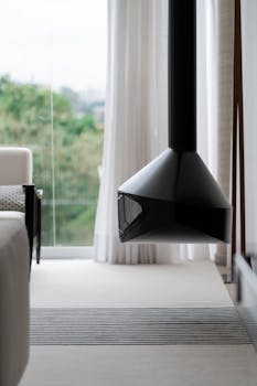 A sleek black hanging fireplace in a stylish, light-filled living room.
