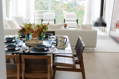 A dining room table with chairs and a vase of flowers