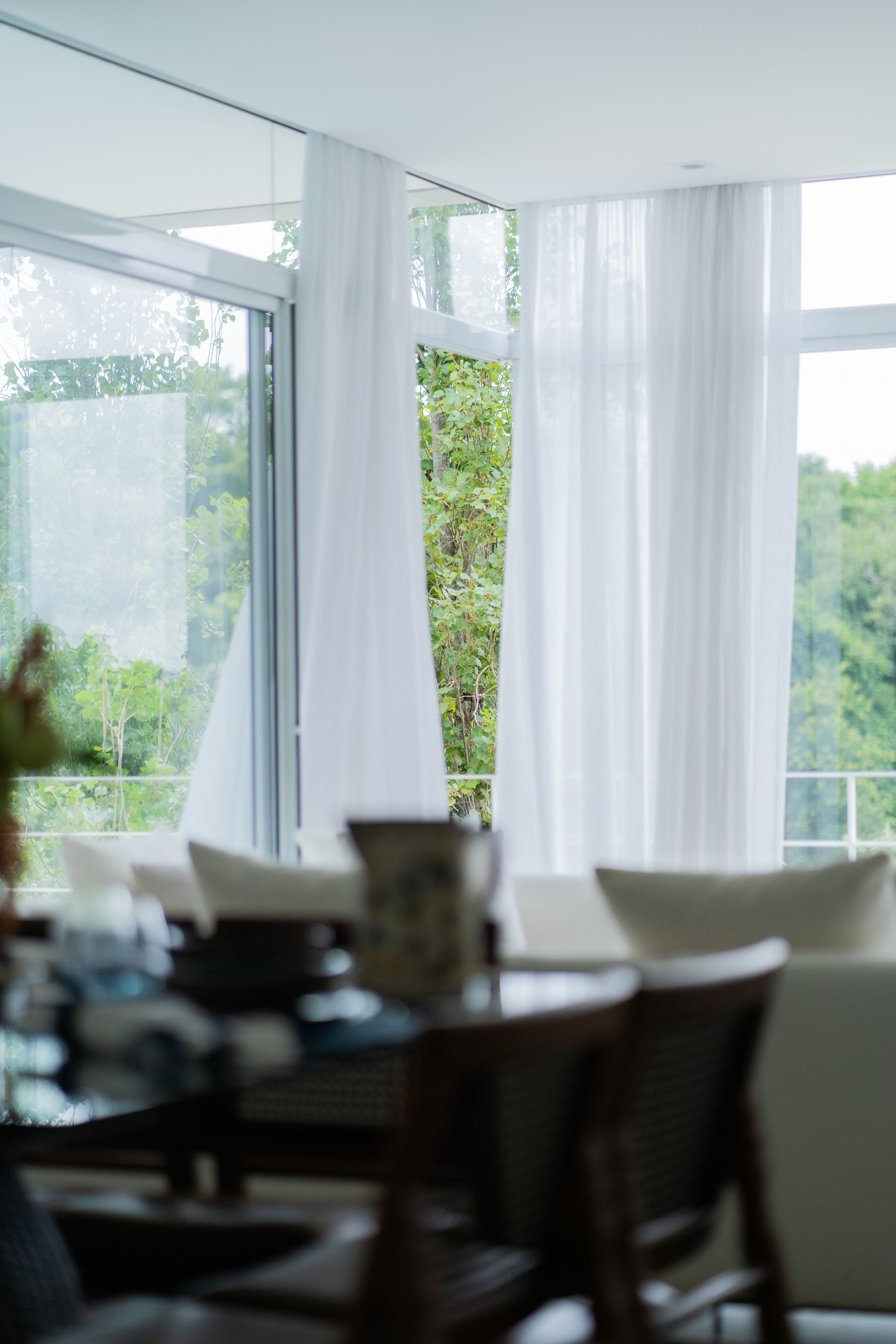 Bright living room with open glazed doors, white curtains and a green view outside