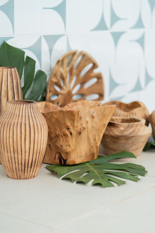 Free A collection of rustic wooden bowls and vases with monstera leaves against a patterned tile background. Stock Photo