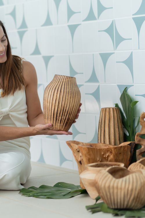 Free Woman holding a wooden vase in a modern rustic setting with decorative elements. Stock Photo