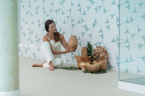 Free Woman admiring rustic wooden vases in a modern interior setting with geometric tiled wall. Stock Photo