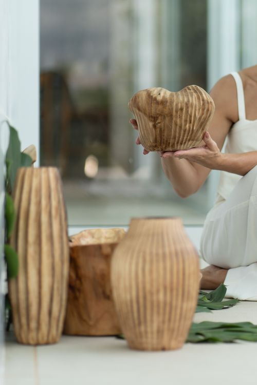 Free Beautiful handcrafted wooden vases with artistic design held by a woman in a modern indoor setting. Stock Photo