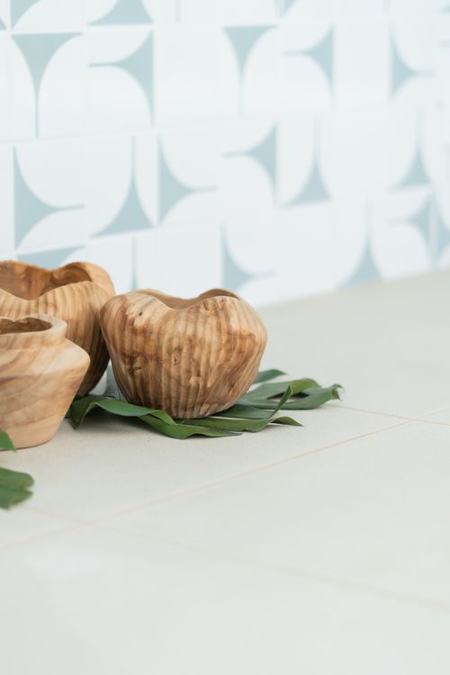 Free Artistic display of carved wooden bowls on green leaves against patterned background. Stock Photo