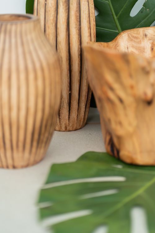 Free Elegant wooden vases accompanied by green monstera leaves, perfect for natural home decor. Stock Photo
