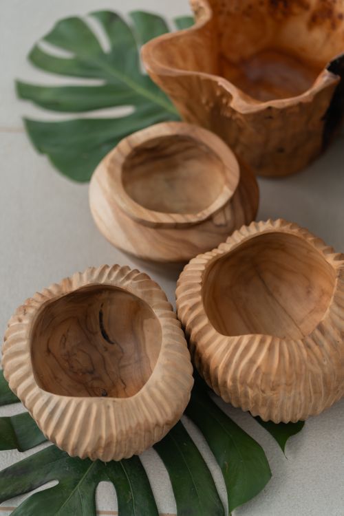 Free A collection of handcrafted wooden bowls displayed on monstera leaves, showcasing natural rustic decor. Stock Photo