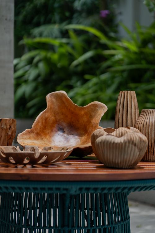Free Handcrafted wooden bowls and vases on an outdoor table with lush greenery backdrop. Stock Photo