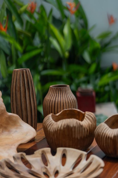 Free Elegant handmade wooden vases displayed against lush green foliage, showcasing natural craftsmanship. Stock Photo