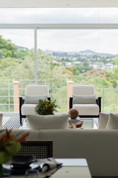 Spacious modern living room with large windows overlooking scenic landscape, featuring luxury furnishings.