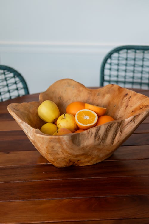 A wooden bowl filled with oranges and lemons