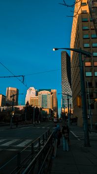 Urban city street with skyscrapers and people under a blue sky at twilight.