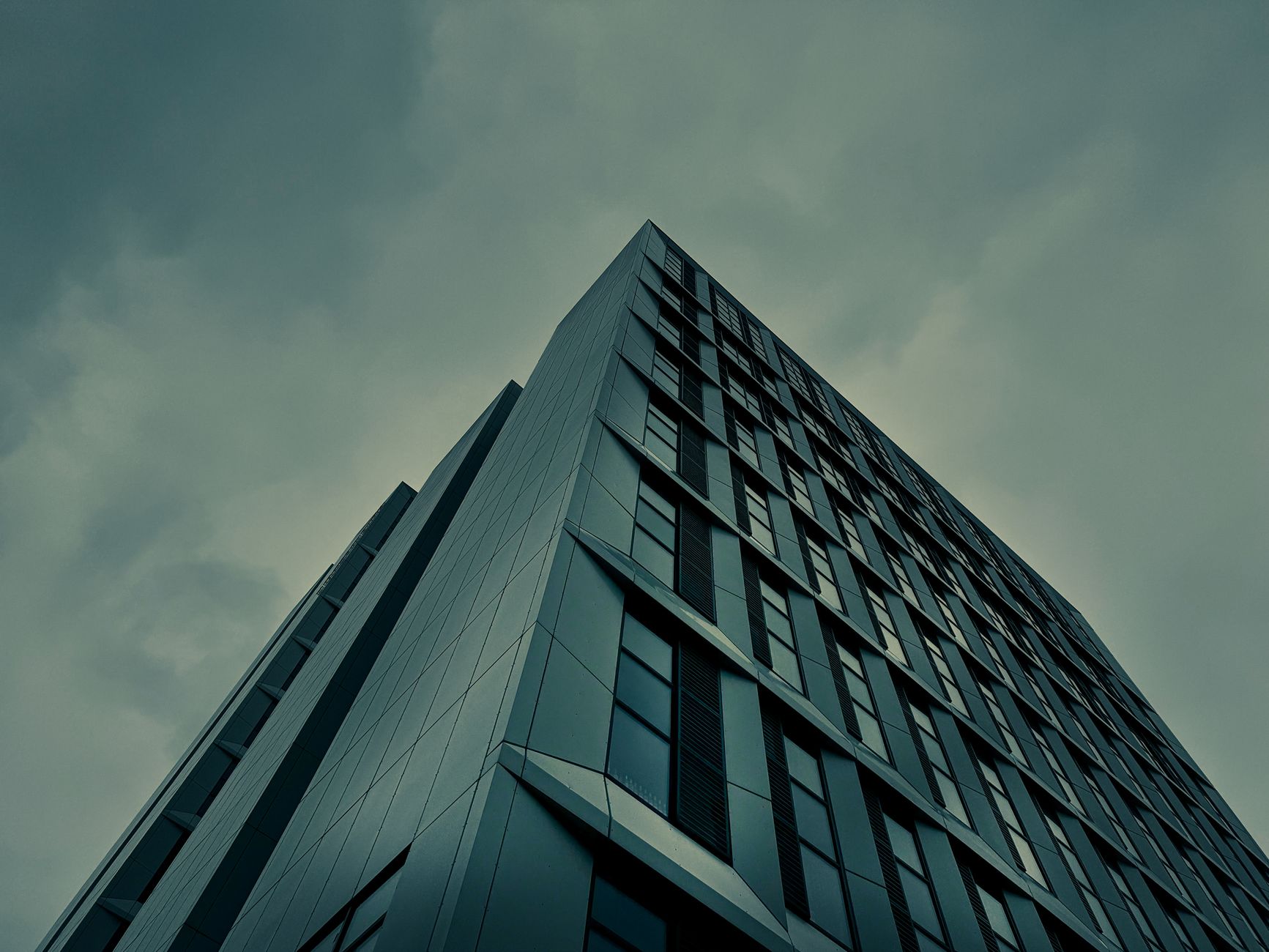Low angle shot of a modern office building with geometric facade in the UK, under overcast skies.