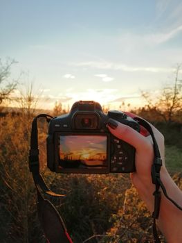 Hand holding a DSLR capturing a sunset in Porto's scenic landscape.
