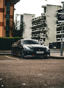 Black sports car with sleek design parked in a city area beside modern architecture.