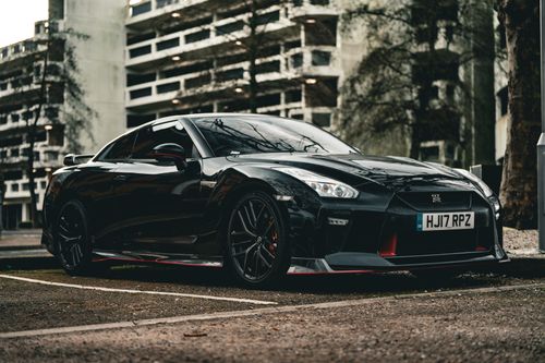 Free A black sports car parked in a city lot, showcasing its sleek design and luxury. Stock Photo