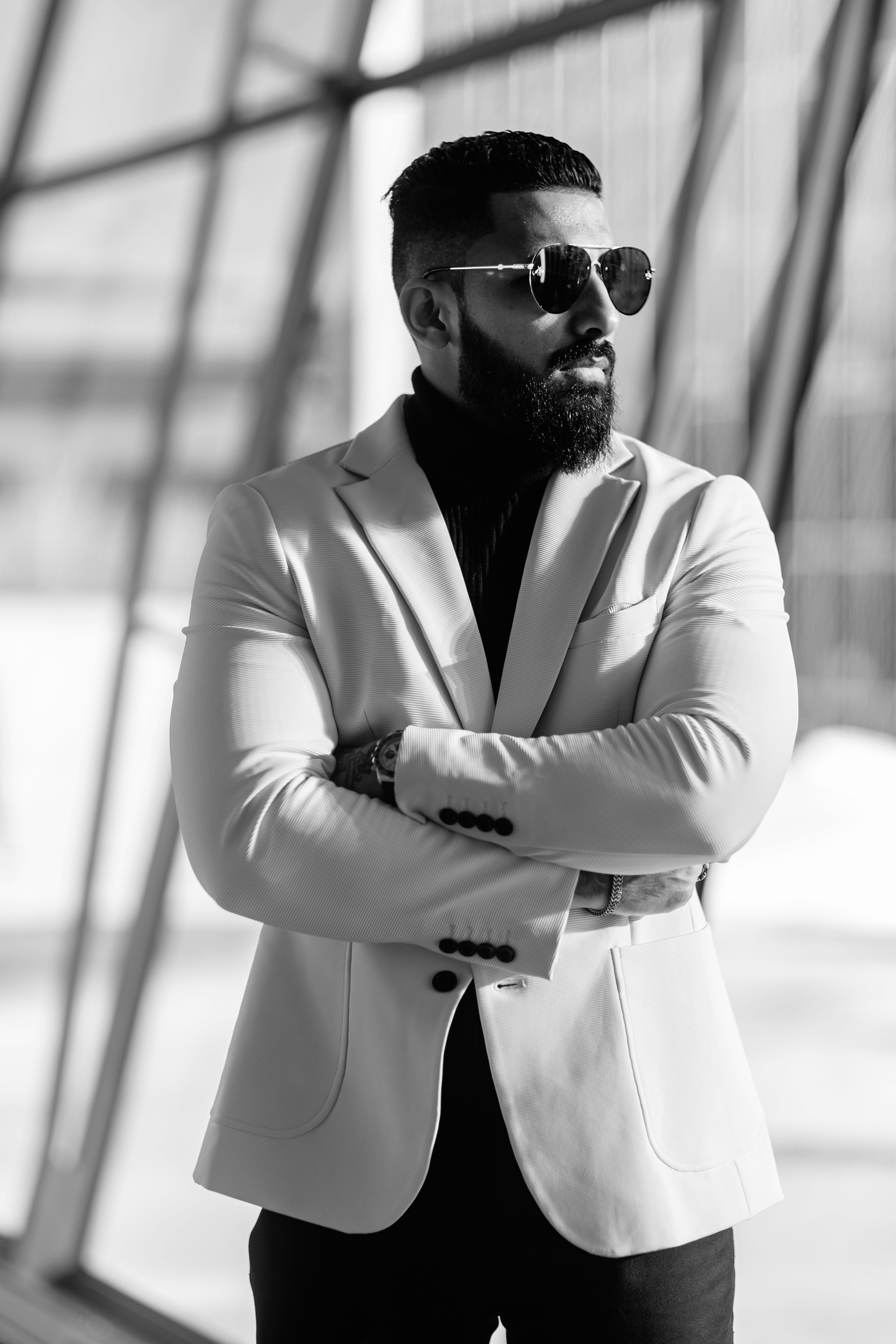 Black and white portrait of a stylish man in sunglasses and white jacket.