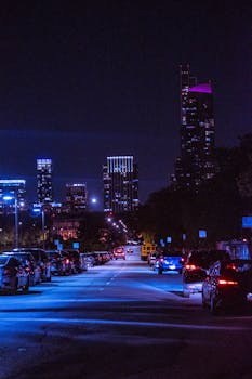 Vibrant city street at night featuring illuminated skyscrapers and busy traffic.
