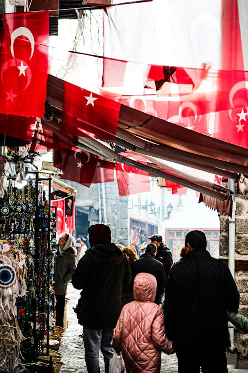 A group of people walking down a street with flags hanging from the ceiling