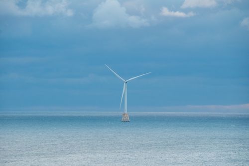 Free A solitary offshore wind turbine stands against a serene seascape in New Shoreham, RI, USA. Stock Photo