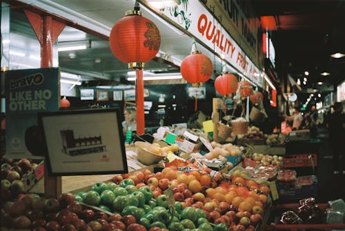 A fruit stand with red and white lanterns hanging from the ceiling