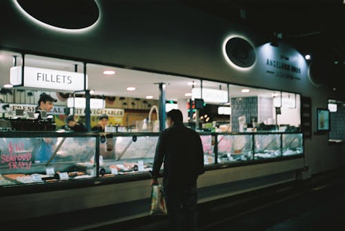 Man Standing at Fishmonger at Night