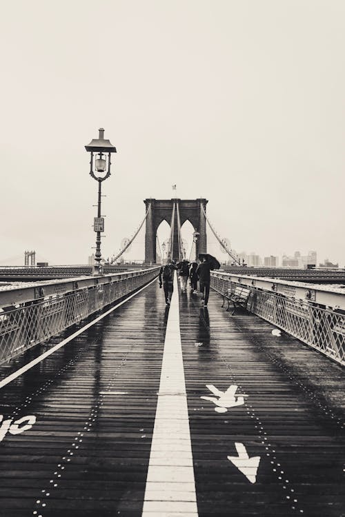 Grayscale Photo of People Walking on a Brooklyn Bridge