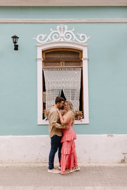 Couple kissing in front of a blue building