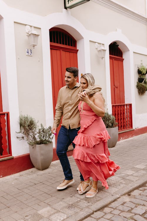 A couple walking down the street in front of a red building