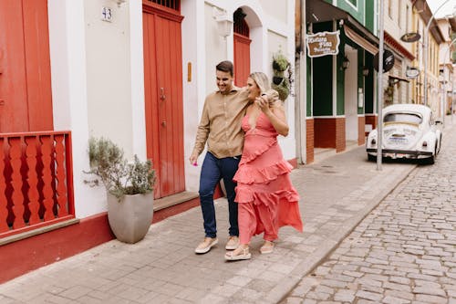 A couple walking down a cobblestone street in a pink dress