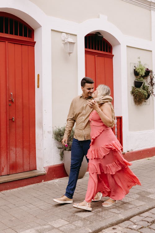 A couple walking down the street in front of a red door