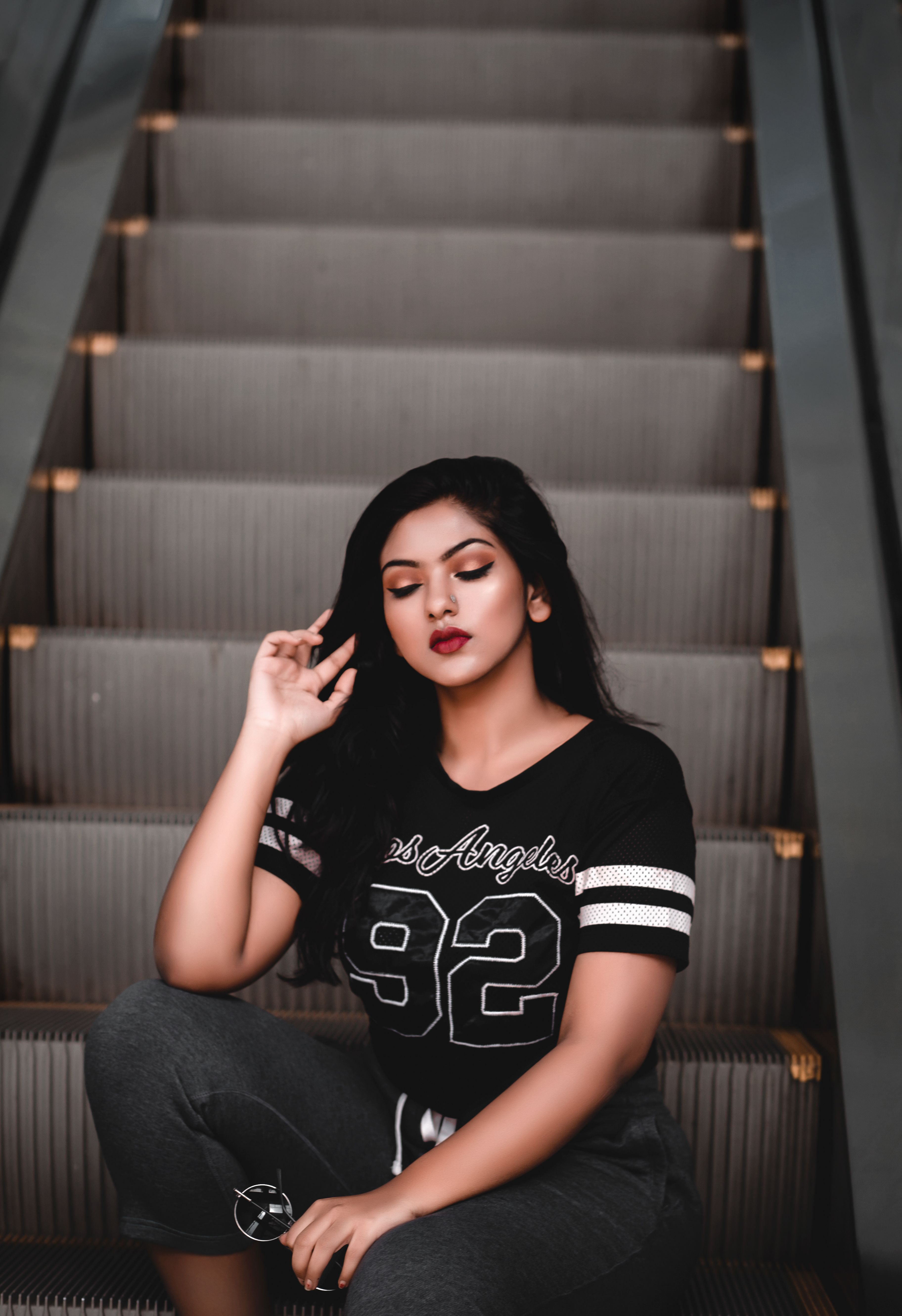 Confident young woman in casual attire posing elegantly on an escalator.