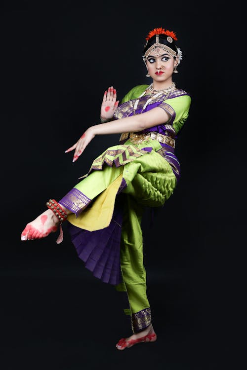 A Dancer in Traditional Clothing and Jewelry Posing against Black Background 