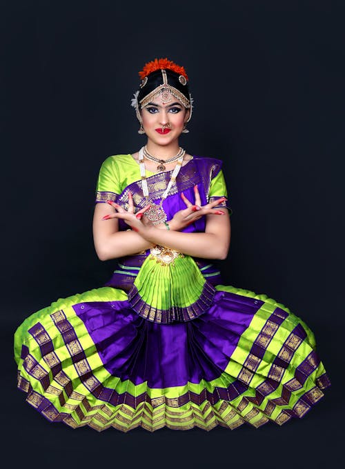 A Woman in Traditional Dress and Jewelry Posing against Black Background 